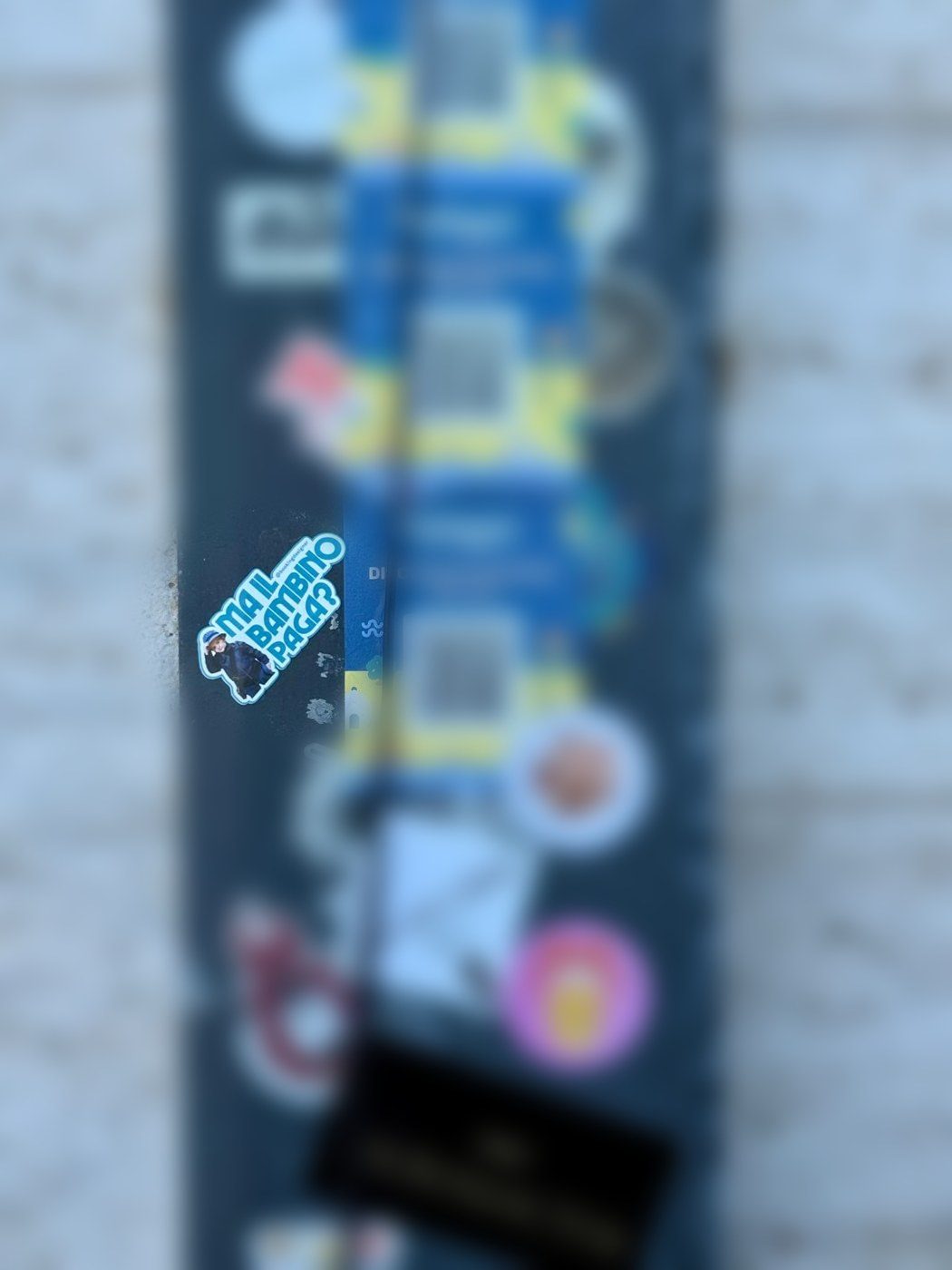 L’adesivo Ma il bambino paga? di Booking Designer attaccato a un palo a Polignano a Mare